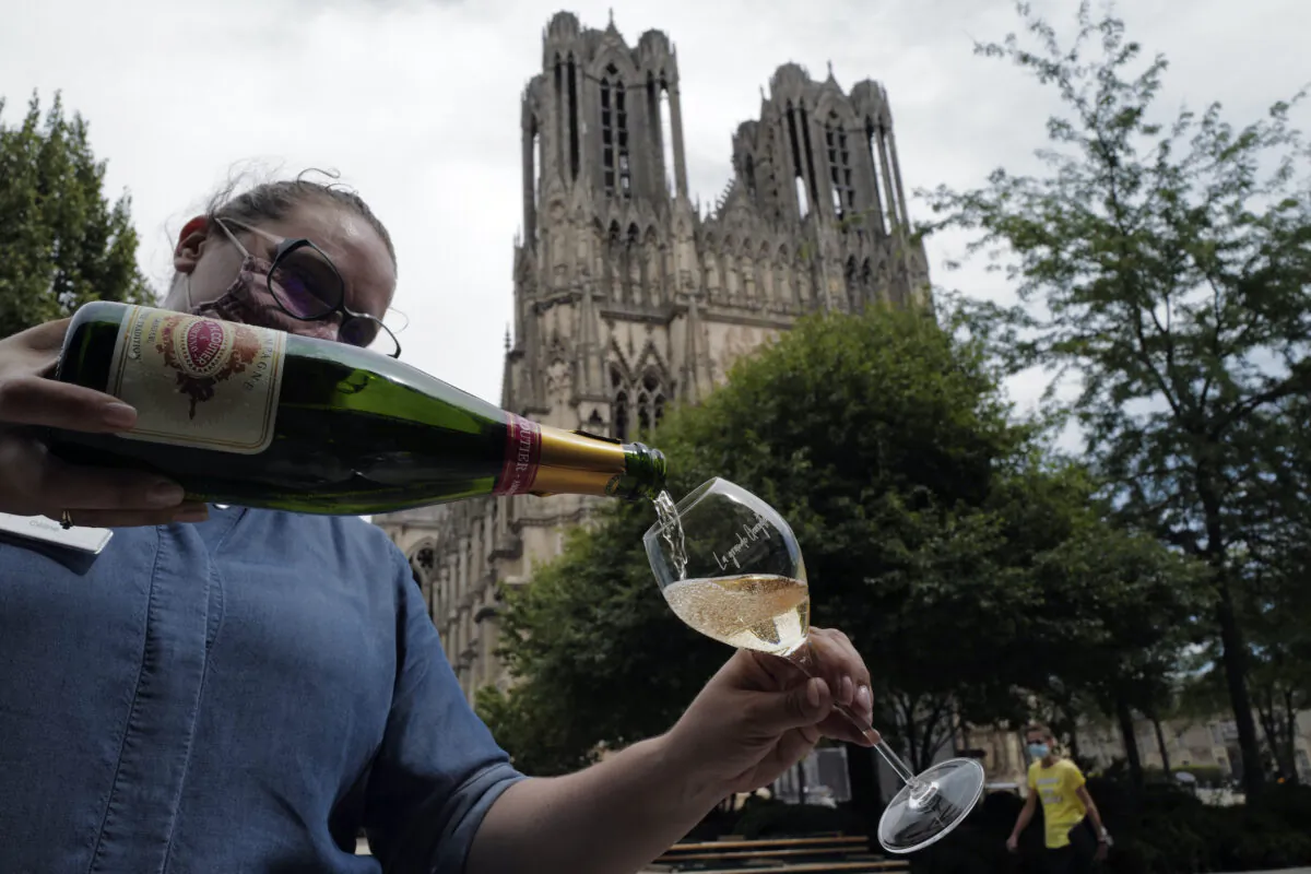 A waitress serves a glass of champagne at La Grande Georgette restaurant in front of the cathedral in Reims, the Champagne region. (AP Photo/Francois Mori)