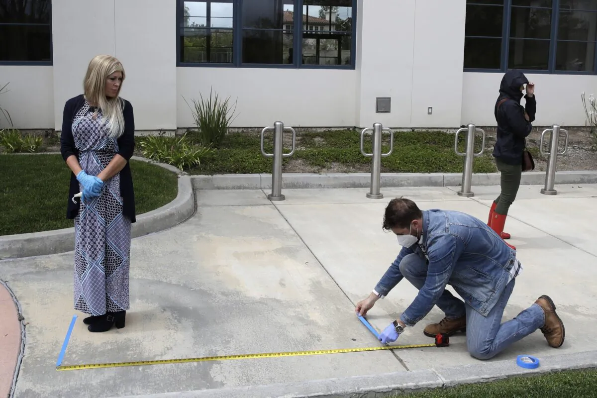 A distance is measured as worshippers line up to take communion on Palm Sunday outside of Godspeak Calvary Chapel in Newbury Park, Calif. on April 5, 2020. (AP Photo/Marcio Jose Sanchez, File)