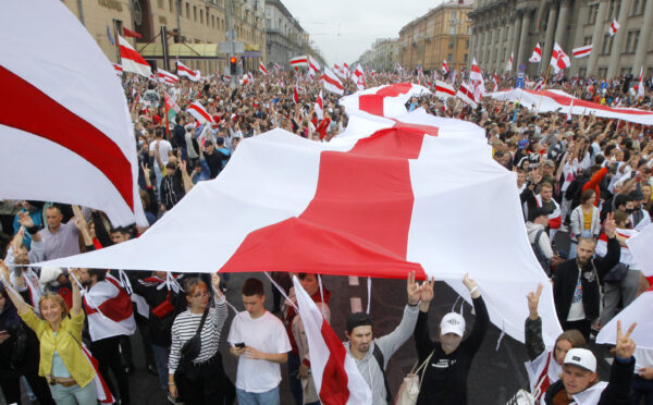 Demonstrators carry a huge historical flag of Belarus