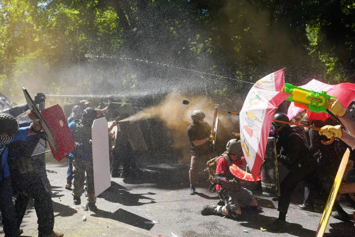 Pro-police demonstrators and others, left, and counter-protesters, fire pepper spray and hurl objects at each other in front of the Multnomah County Justice Center in Portland, Ore., on Aug. 22, 2020. (Nathan Howard/Getty Images)