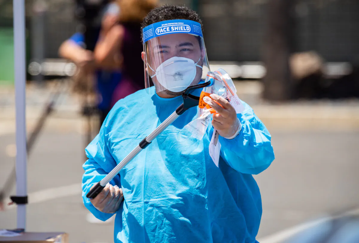 A worker handles a swab test for COVID-19 at a testing site at the Anaheim Convention Center, in Anaheim, Calif., on July 15, 2020. (John Fredricks/The Epoch Times)