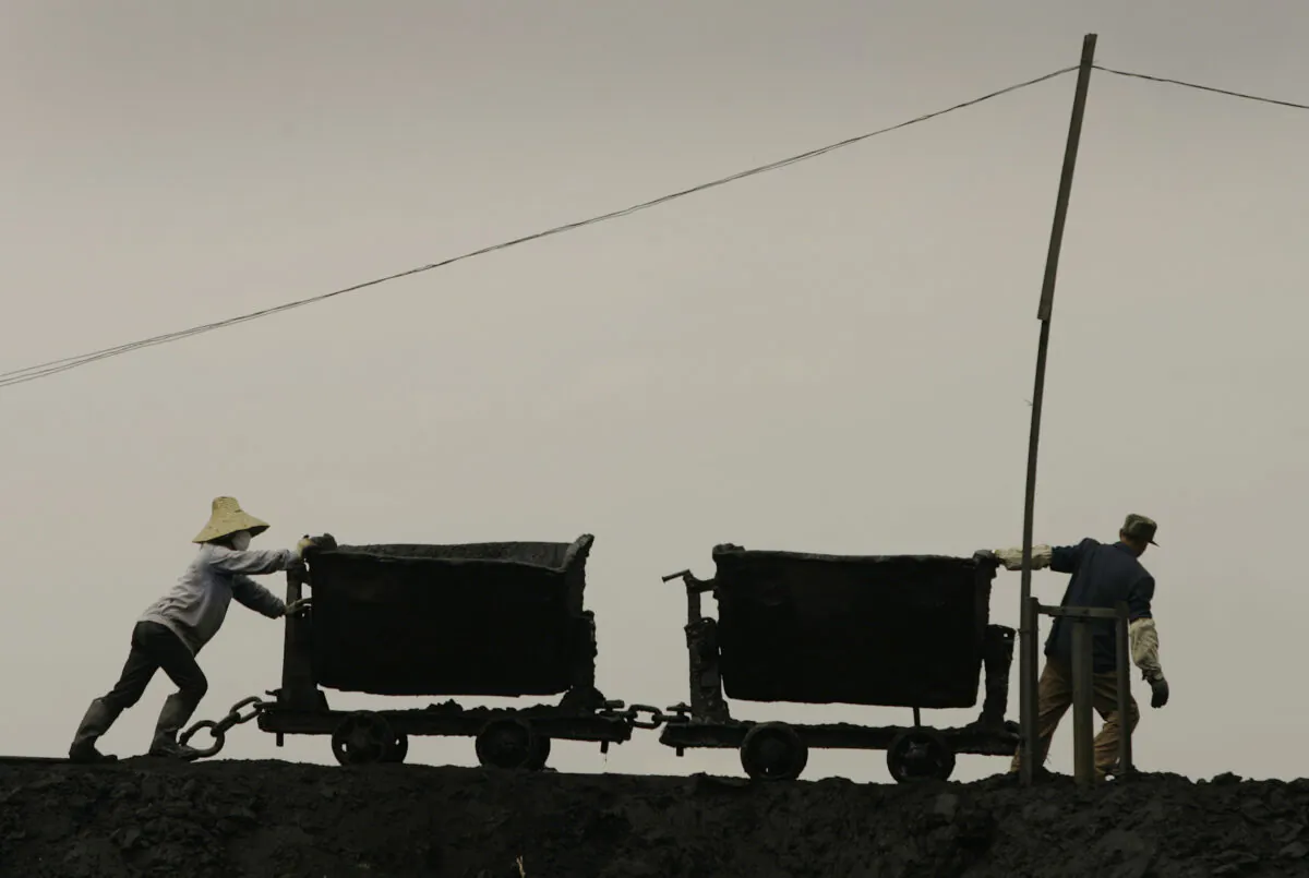 Workers pull coal wagons at the Beichang coal washery in Jixi City in China's Heilongjiang Province, on June 4, 2006. (Peter Parks/AFP via Getty Images)