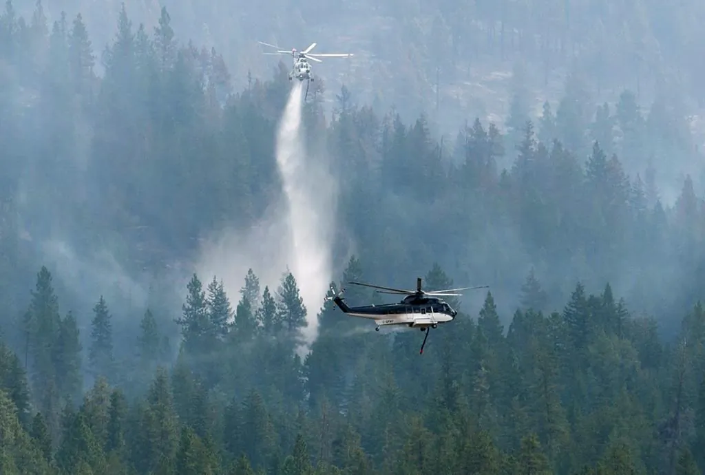 Helicopters drop water on the Christie Mountain wildfire along Skaha Lake in Penticton, B.C., on Aug. 21, 2020. (The Canadian Press/Jonathan Hayward)