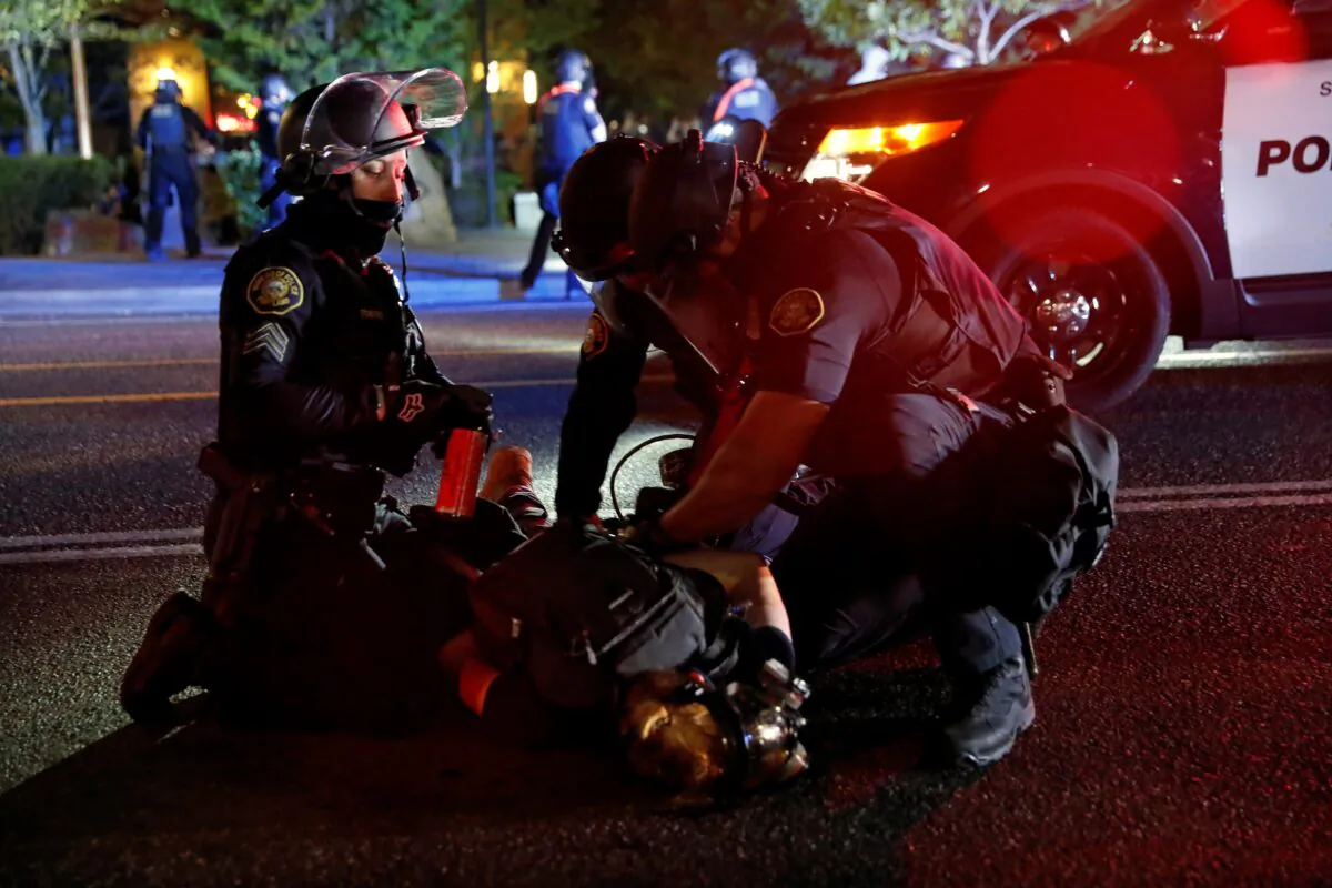 Police officers detain a demonstrator during a riot in Portland, Ore., on Aug. 24, 2020. (Terray Sylvester/Reuters)