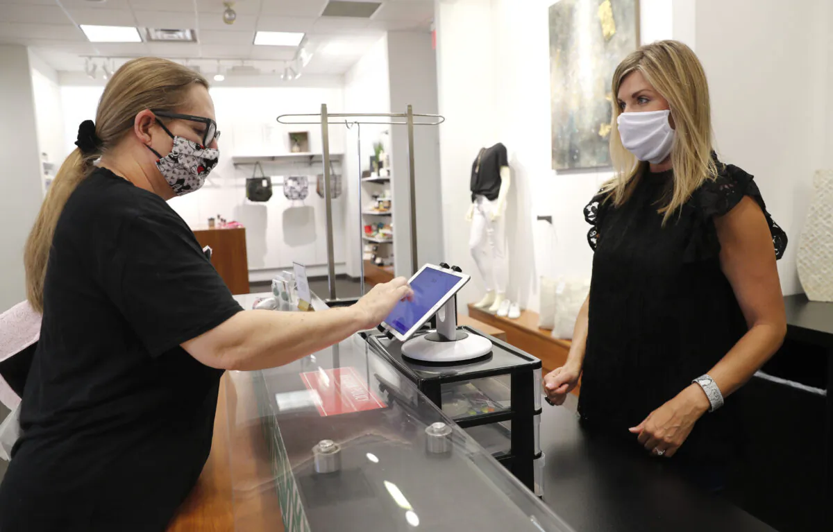 Monique Kursar, left, completes a purchase with Amy Witt, owner of the Velvet Window, in Dallas on May 13, 2020. (LM Otero/AP Photo)