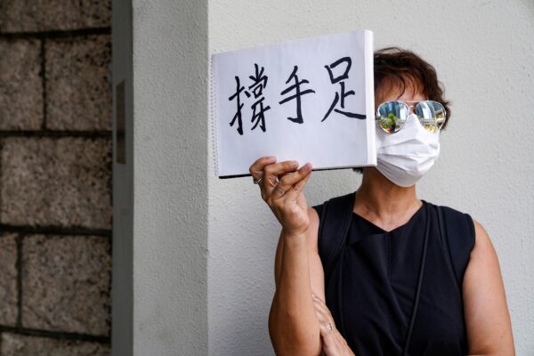 A woman holds up a paper pad that reads "support sibling" while waiting outside the court