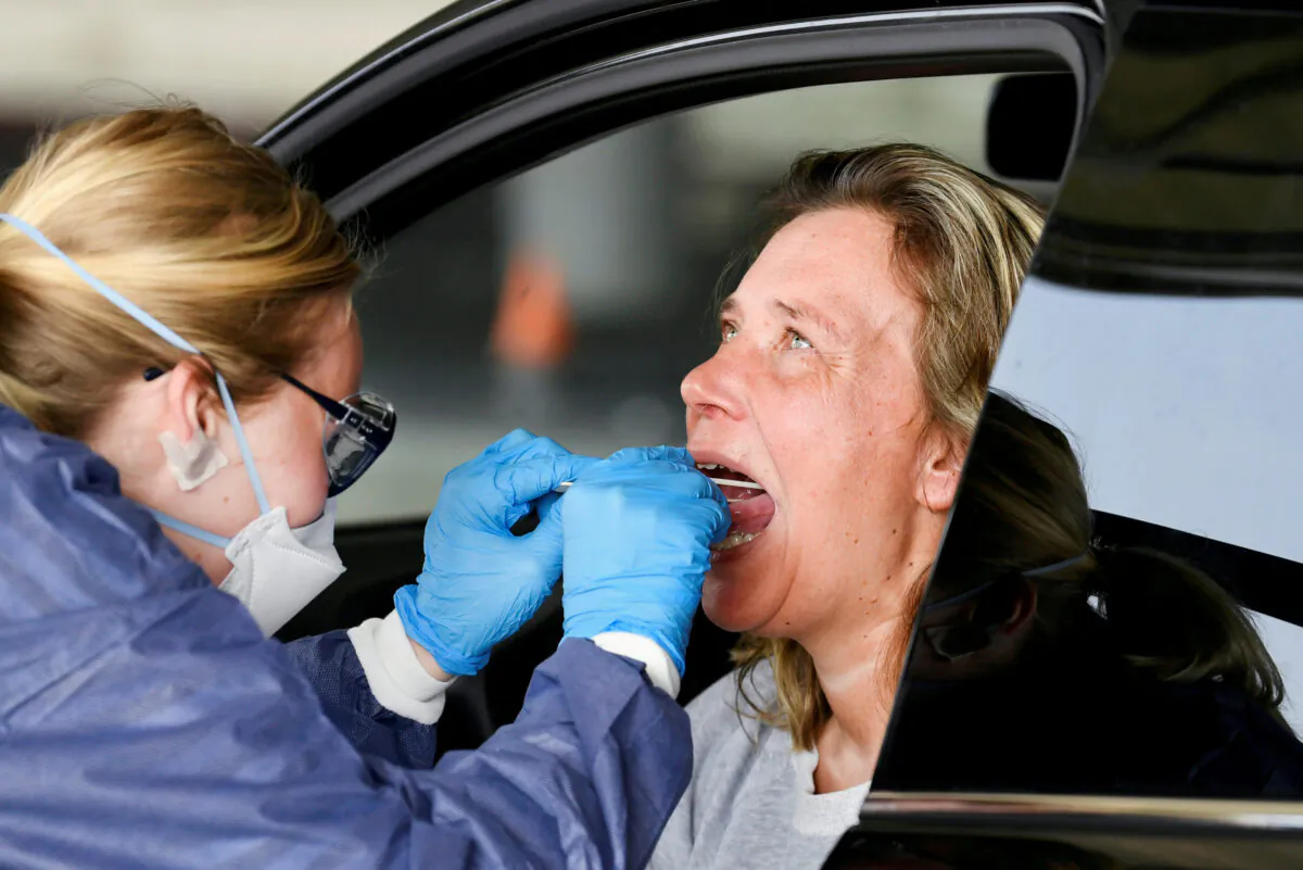 A medical staff member takes CCP virus test samples from a woman at a converted ice rink, in Alkmaar, Netherlands, on April 8, 2020. (Piroschka van de Wouw/Reuters)


