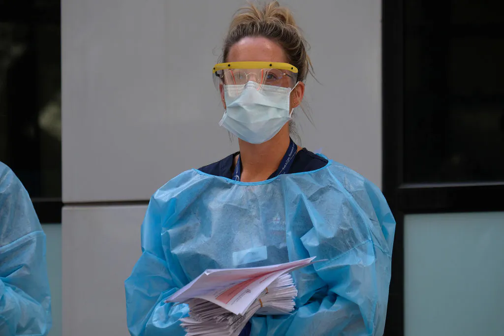 Hospital staff assist people waiting in line to be screened for COVID-19 outside the Royal Melbourne Hospital on March 11, 2020 in Melbourne, Australia. (Luis Ascui/Getty Images)