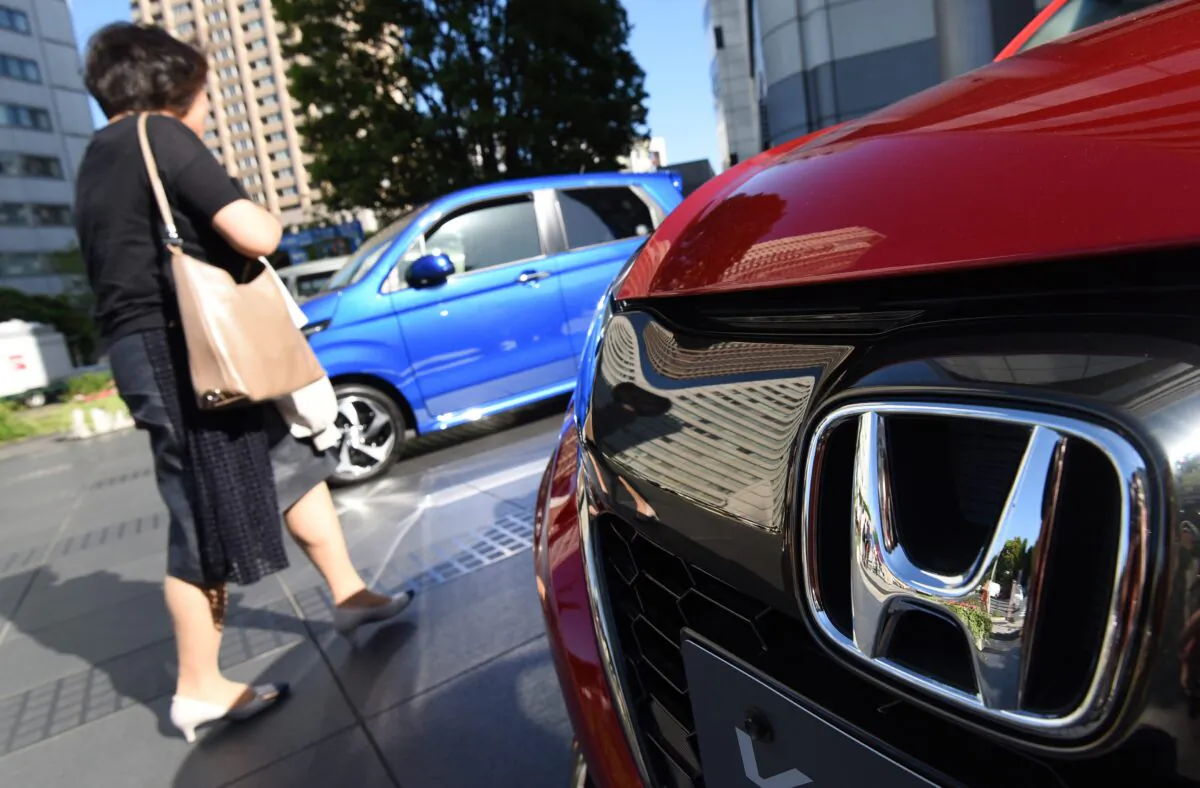 A woman walks past vehicles by Japan's Honda Motor at the company's headquarters in Tokyo, Japan, on May 13, 2016. (Toru Yamanaka/AFP via Getty Images)