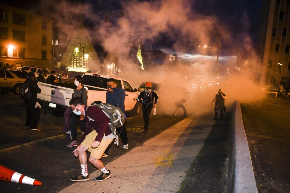 People run from tear gas thrown by the police near the Colorado State Capitol during rioting in Denver, Colo., on May 30, 2020. (Michael Ciaglo/Getty Images)