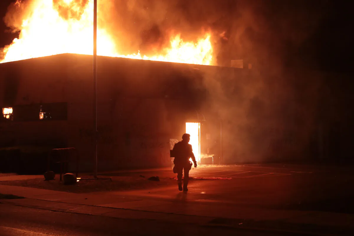 A police officer stands guard in front of a Department of Corrections building after it was set on fire during rioting in Kenosha, Wis., on Aug. 24, 2020. (Scott Olson/Getty Images)