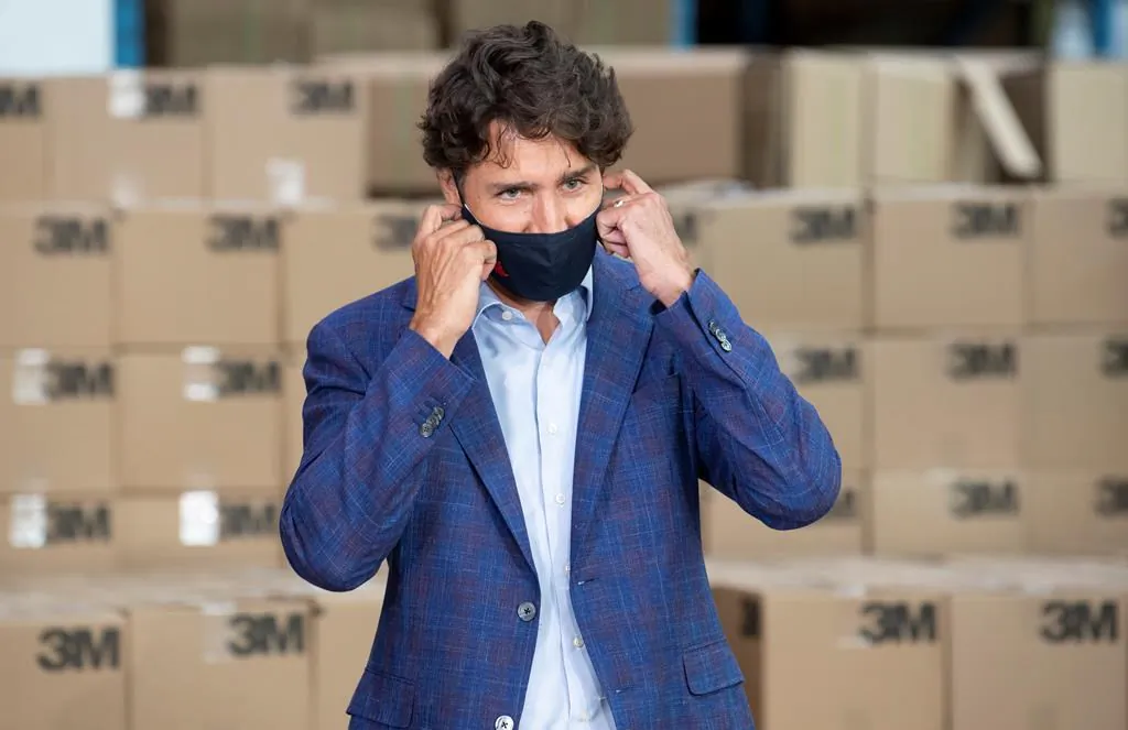 Prime Minister Justin Trudeau removes a cloth mask as he approaches the podium during an announcement at a factory in Brockville, Ont., on Aug. 21, 2020. (Adrian Wyld/The Canadian Press)