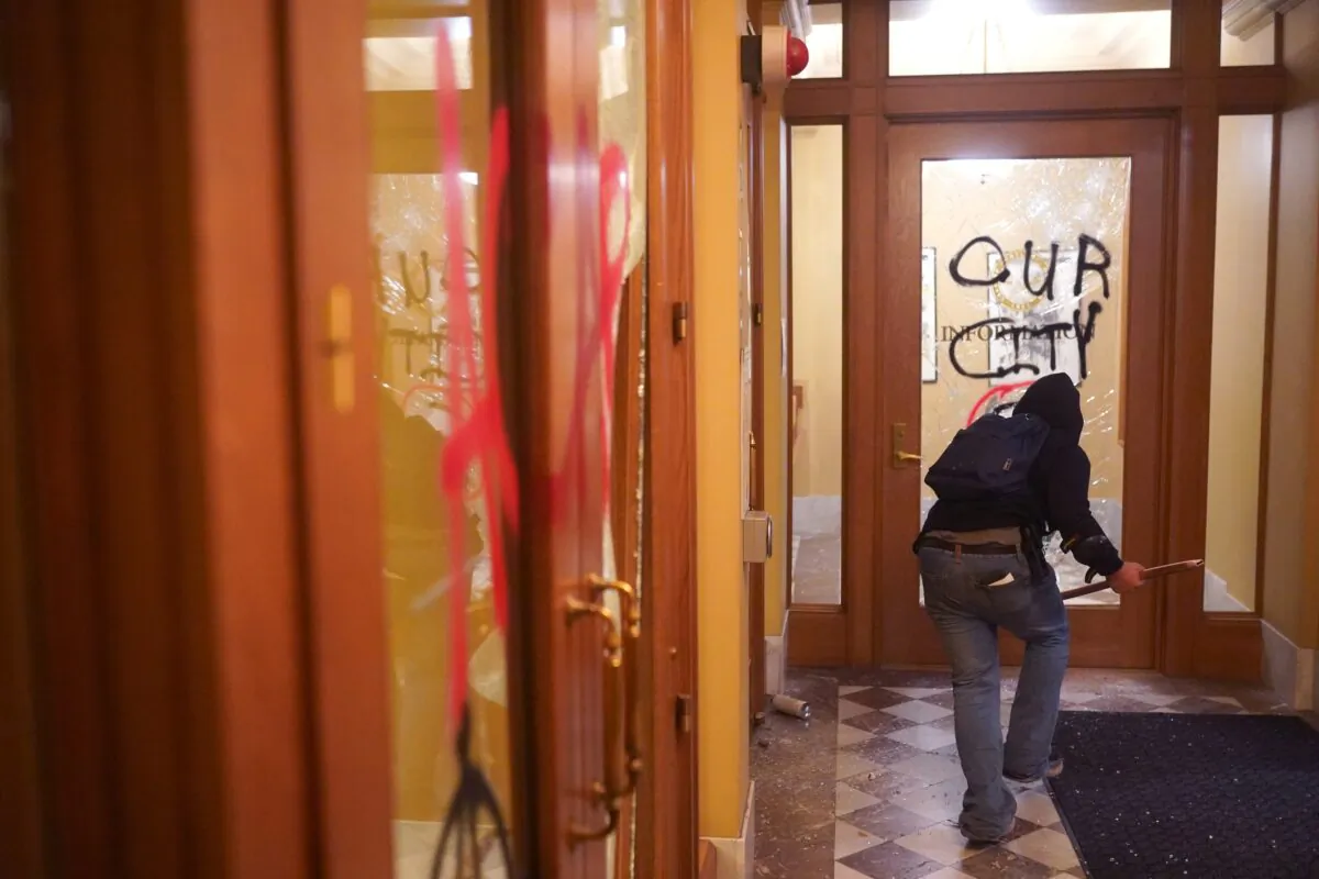 A rioter runs through the vandalized lobby of City Hall in Portland, Ore., on Aug. 25, 2020. (Nathan Howard/Getty Images)