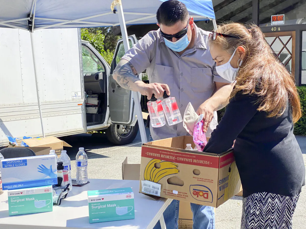 Alondra Klemek (R) picks up a box of supplies from a re-entry pod at the Chevron gas station in Carmel Valley, Calif. on Aug. 26, 2020. (Nancy Han/NTD)