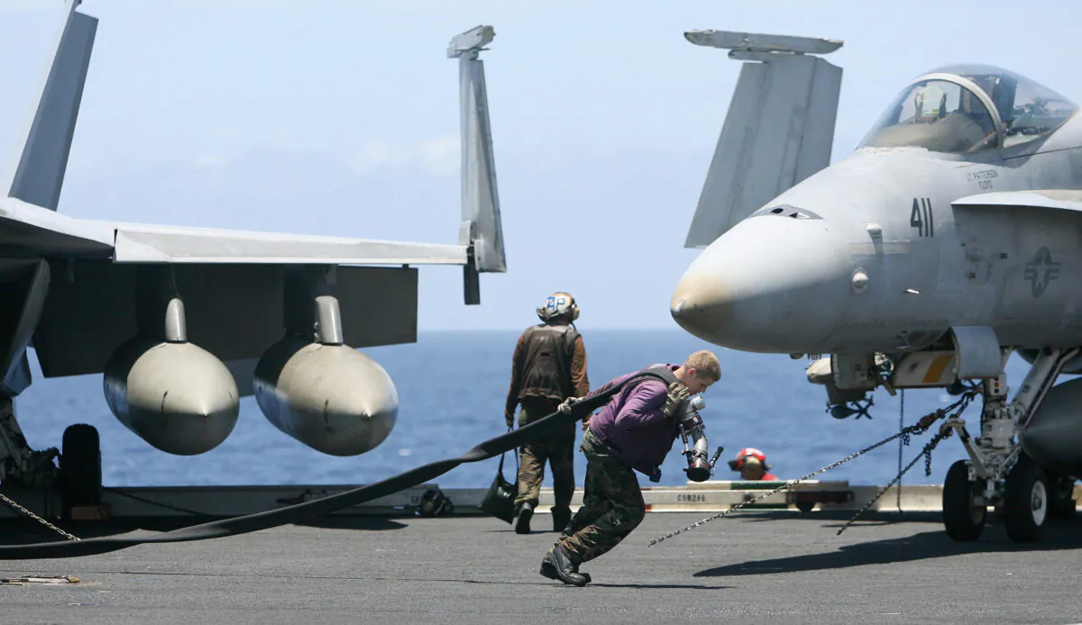 A US Navy crewman pulls a fuel pipe across the deck of USS Kitty Hawk (CV63) aircraft carrier in the Bay of Bengal, during the Malabar exercise on Sep. 7, 2007. (Deshkalyan Chowdhury/AFP via Getty Images)