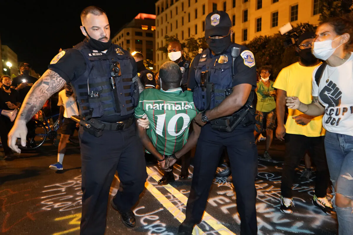 Police carry away a handcuffed protestor along a section of 16th Street, Northwest, renamed Black Lives Matter Plaza, in Washington, on Aug. 27, 2020. (Julio Cortez/AP Photo)