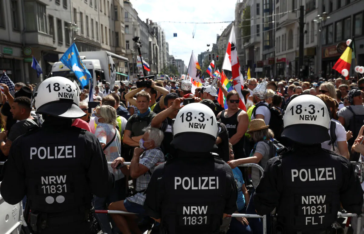 Police officers stand in front of demonstrators as they attend a rally against the government's restrictions following the CCP virus disease (COVID-19) outbreak, in Berlin, Aug. 29, 2020. (Christian Mang/Reuters)