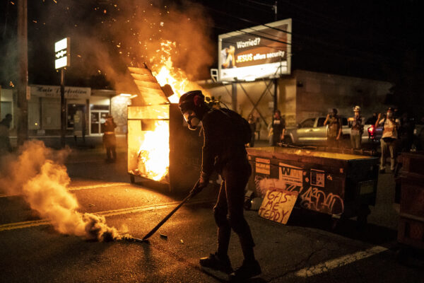 A protester walks past a dumpster fire early in the morning on Aug. 29, 2020 in Portland, Oregon. (Nathan Howard/Getty Images)