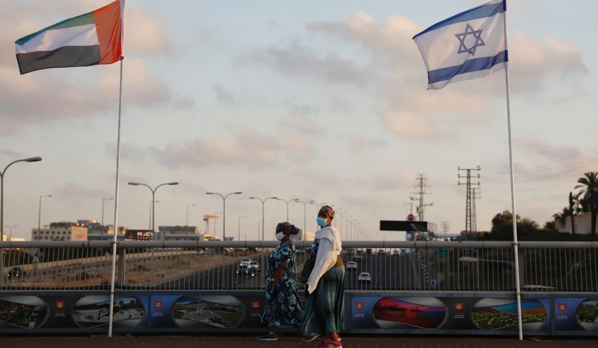 Women wearing face masks against the coronavirus walk past United Arab Emirates and Israeli flags at the Peace Bridge in Netanya, Israel, Sun., Aug. 16, 2020. (Ariel Schalit/AP Photo)