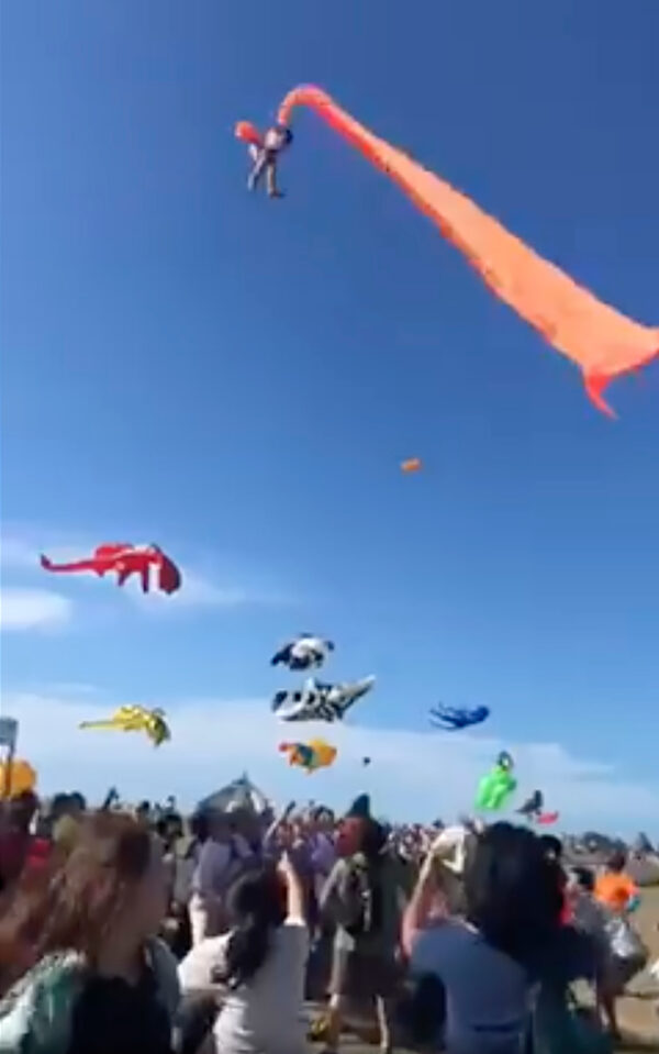 A 3 year old girl is lifted into the air by a large kite