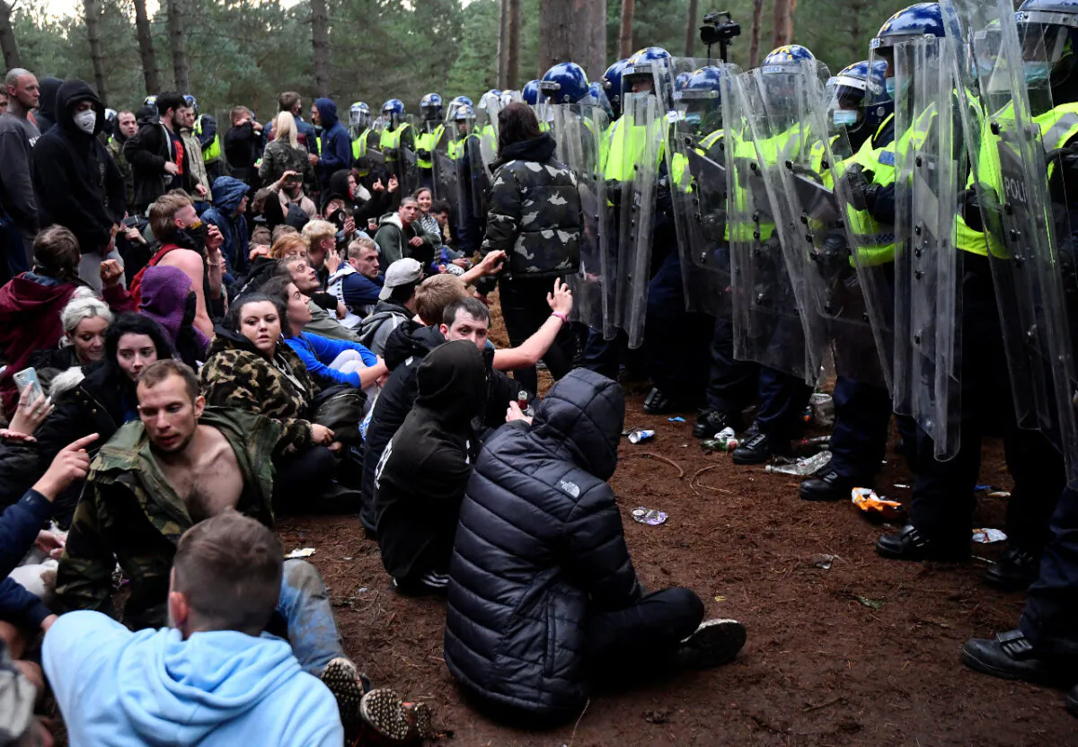 Revellers sit after police shut down a suspected illegal rave in Thetford Forest, in Norfolk, Britain on Aug. 30, 2020. (Reuters/Toby Melville)