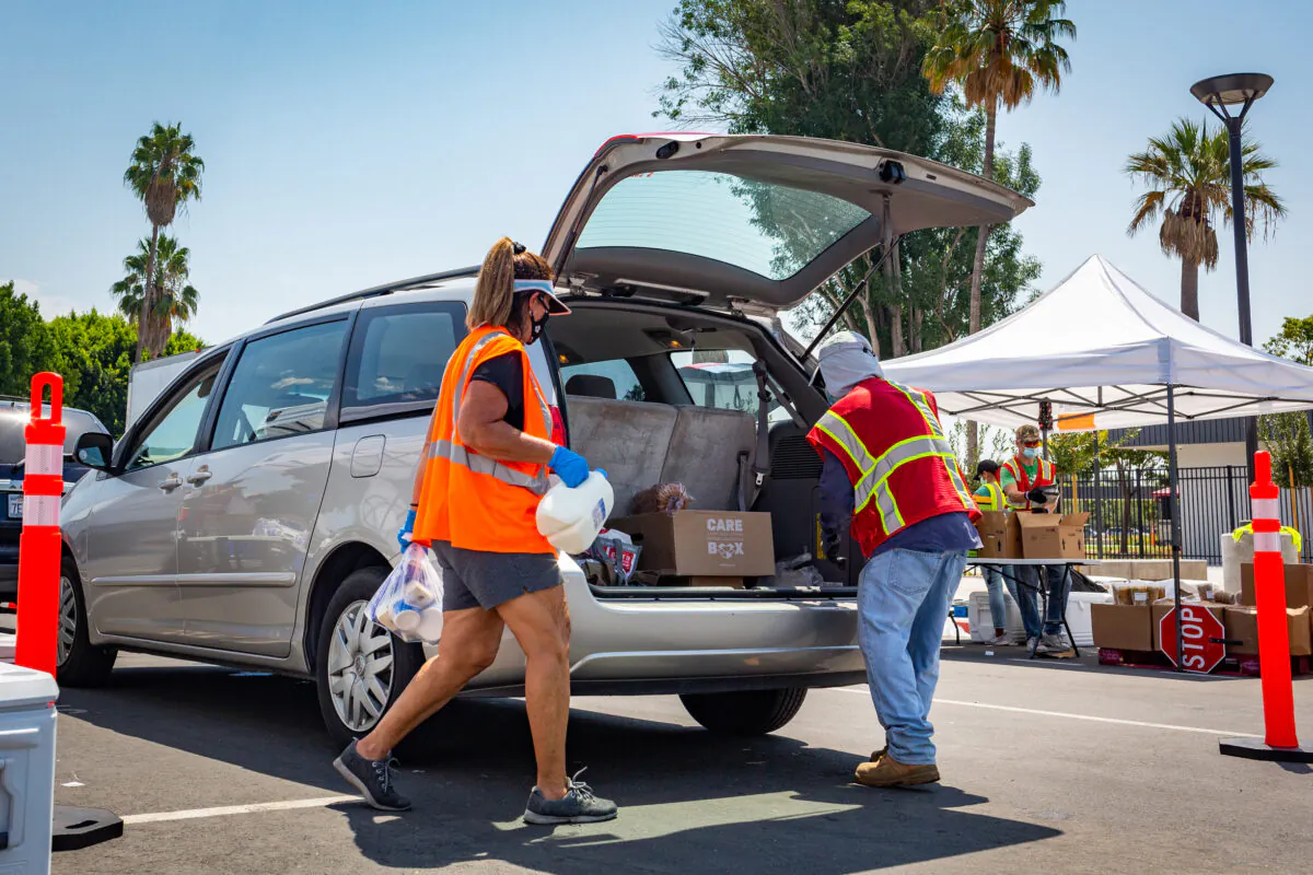 Saddleback Church Food Pantry volunteers help load food items into the back of an SUV at Savanna High School in Anaheim, Calif., on Aug. 18, 2020. (John Fredricks/The Epoch Times)