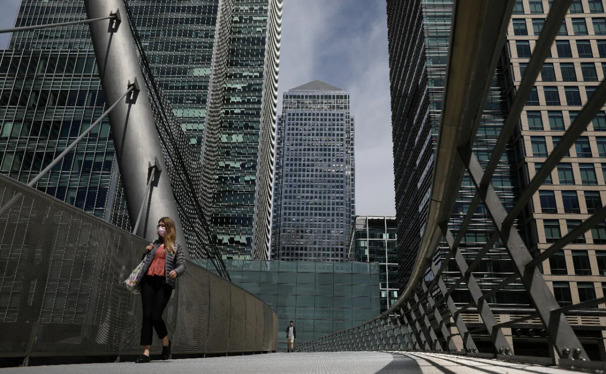 In this file photo a woman wearing a face mask crosses a bridge in front of One Canada Square in Canary Wharf following the outbreak of the CCP virus in London, on May 18, 2020. (Reuters/Simon Dawson)