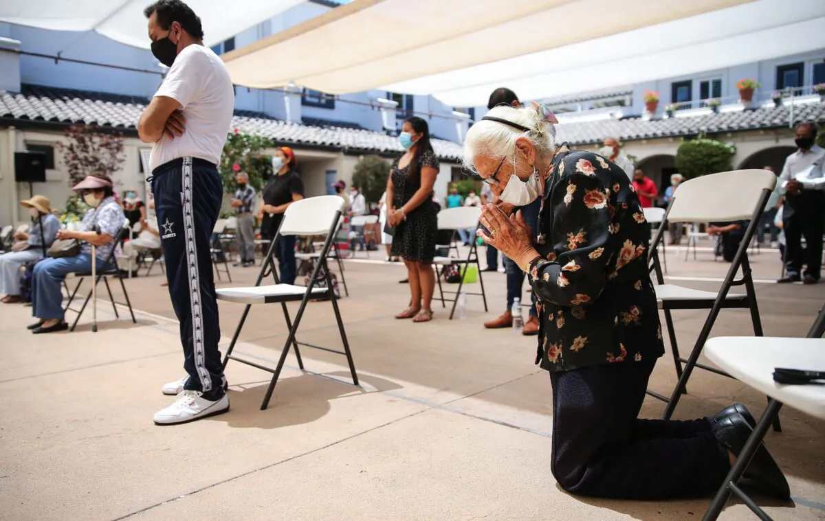 A worshipper kneels in prayer during Mass celebrated outdoors at the historic Our Lady Queen of Angels (La Placita) Church amid the COVID-19 pandemic in Los Angeles on Aug. 9, 2020. (Mario Tama/Getty Images)