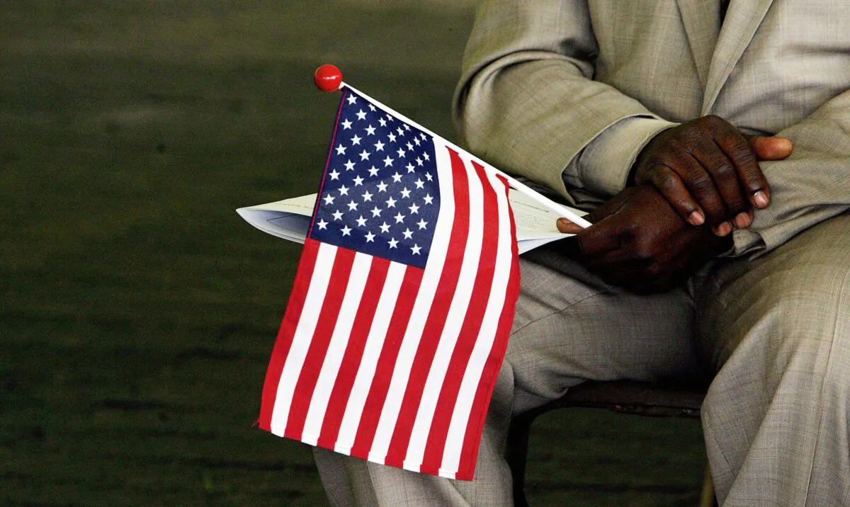 Jeneba Kanu, originally from Sierra Leone, holds a U.S. flag while waiting to become a U.S. citizen, during a naturalization ceremony at George Washington's Mount Vernon in Alexandria, Va., on May 22, 2006. (Jim Watson/AFP via Getty Images)