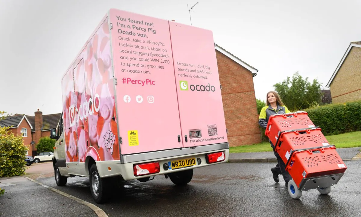 An Ocado delivery worker moves products beside one of the 10 Percy Pig branded Ocado vans, in Britain, on Sept. 1, 2020. (Doug Peters/PA Wire via Ocado)