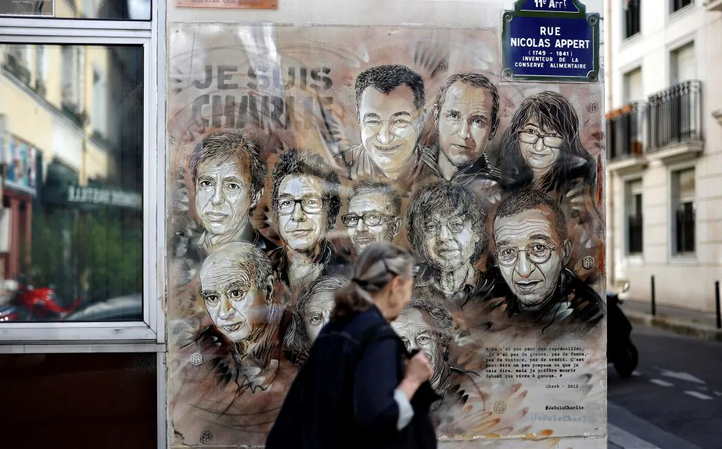 A woman walks past a painting by French street artist and painter Christian Guemy in tribute to members of Charlie Hebdo newspaper who were killed by jihadist gunmen in January 2015, in Paris, on Aug. 31, 2020. (Thomas Coex/AFP via Getty Images)