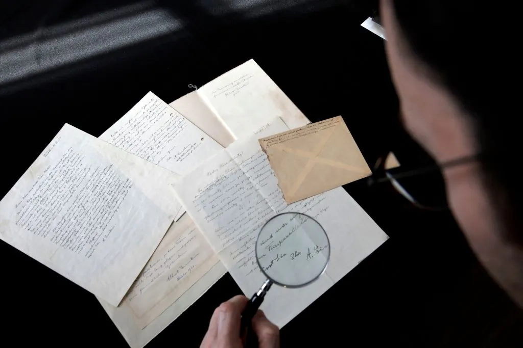An employee uses a magnifying glass to inspect a series of letters by Nobel Prize-winning physicist Albert Einstein at Winner's auction house in Jerusalem, on March 6, 2018 prior to being auctioned later in the night with the rest of a series of nine. / AFP PHOTO / MENAHEM KAHANA        (Photo credit should read MENAHEM KAHANA/AFP via Getty Images)
