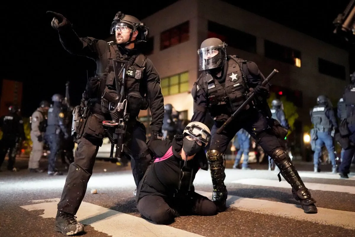 Portland police and Oregon State Patrol officers work together to arrest a woman during rioting in Portland, Ore., on Aug. 11, 2020. (Nathan Howard/Getty Images)