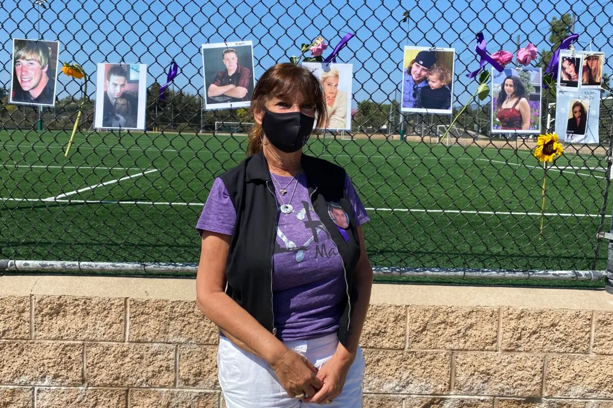 Event coordinator Jodi Barber stands in front of a chain-link fence lined with pictures of overdose victims on International Overdose Awareness Day at the Laguna Niguel Skate Park in Laguna Niguel, Calif., on Aug. 31, 2020. (Chris Karr/The Epoch Times)
