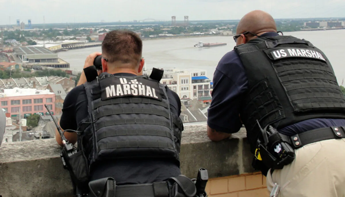 Two U.S. Marshals stand on a building as they look out toward the city in a file photo. (Illustration - Elliott Cowand Jr/Shutterstock)