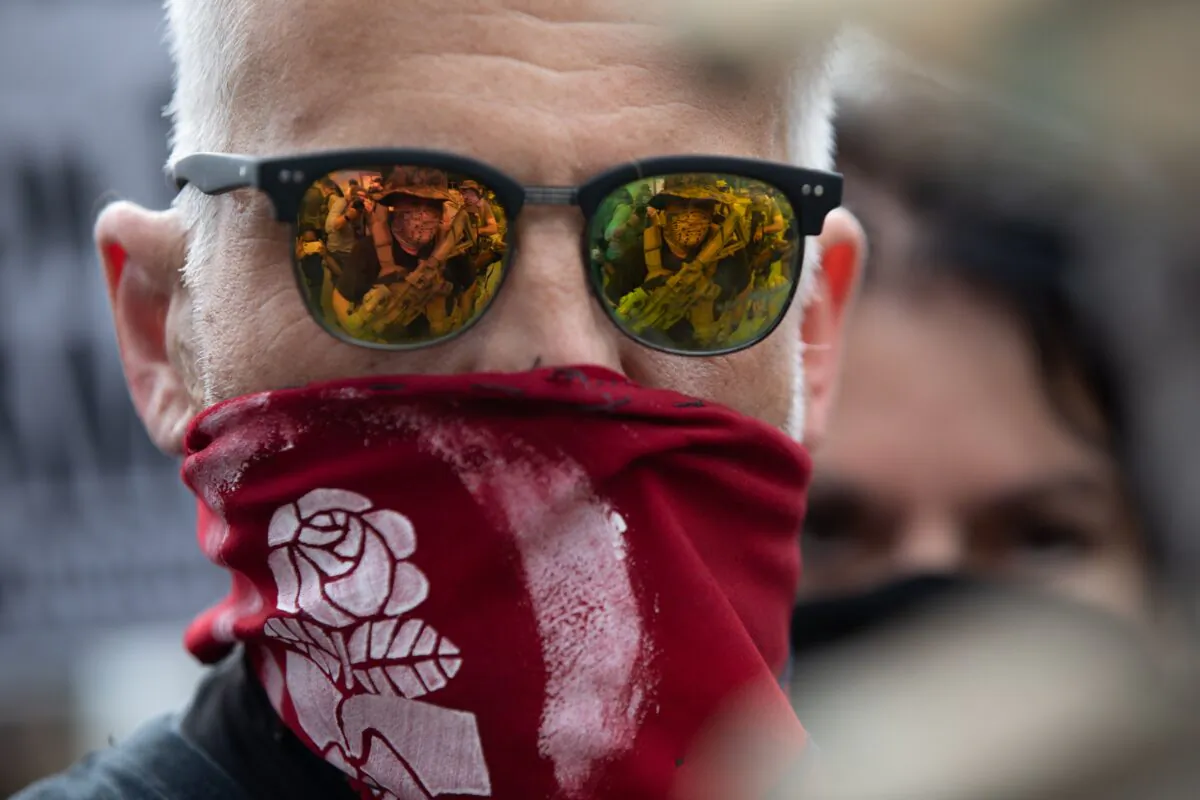 A militia member is seen reflected in the glasses of an Antifa demonstrator during a rally and counter-demonstration in Stone Mountain, Ga., on Aug. 15, 2020. (Logan Cyrus/AFP via Getty Images)