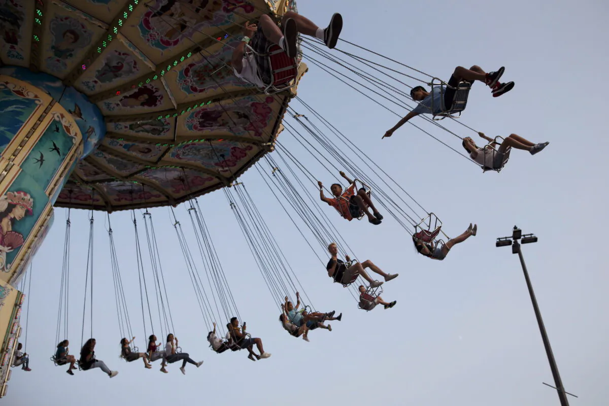 Children swing on a midway ride at the 140th annual Canadian National Exhibition in Toronto on August 19, 2018. (The Canadian Press/Cole Burston)