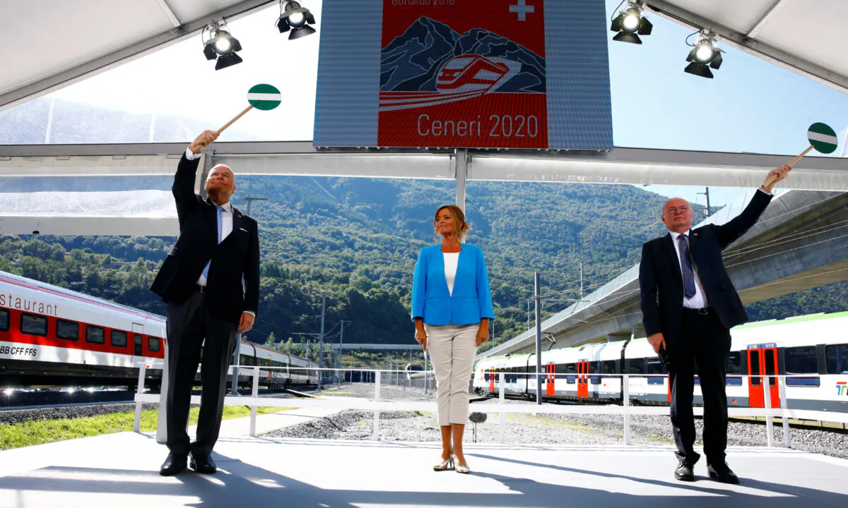 CEO of Swiss Federal Railways (SBB) Vincent Ducrot (R) and CEO AlpTransit Gotthard Dieter Schwank wave signalling discs during the opening ceremony of the newly built Ceneri Base Tunnel, on Sept. 4, 2020. (Arnd Wiegmann/Reuters)