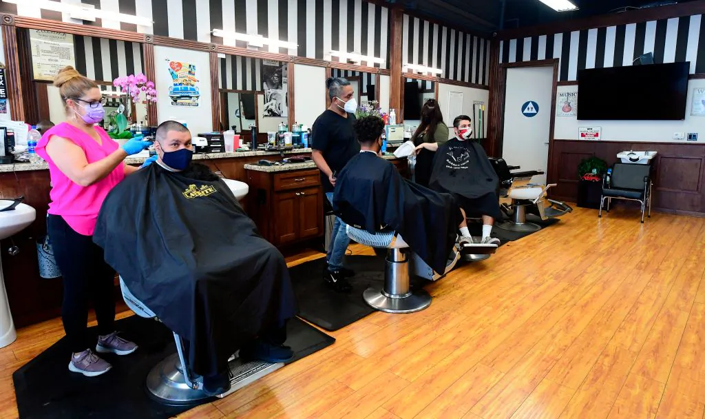 Hairdressers work on customers seated inside for the first time in months at Angelo's Barber Shop in downtown Los Angeles on Sept. 3, 2020. (Frederic J. Brown/AFP via Getty Images)