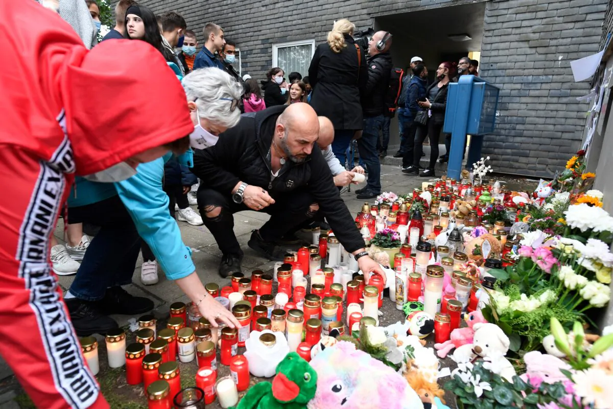 Neighbour Kasim Ayten and other people lay stuffed animals, flowers and candles in front of the house where five children were found dead in Solingen, Germany, on Saturday, Sept. 5, 2020. (Roberto Pfeil/dpa via AP)