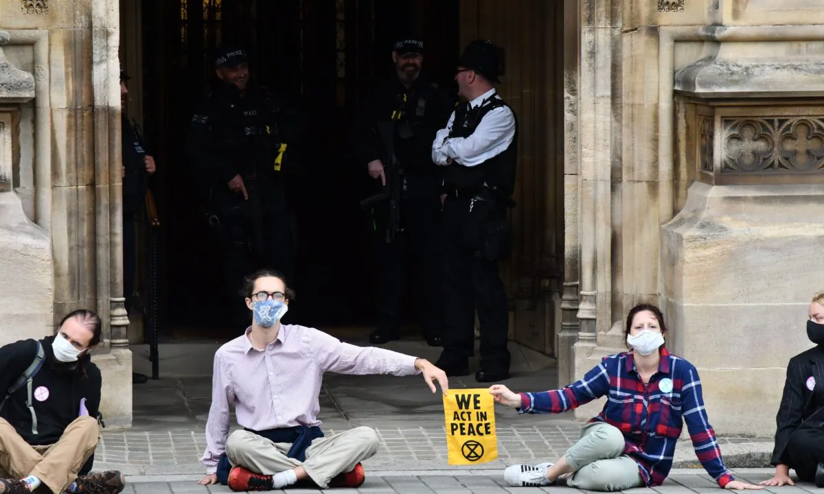Activists from the climate protest group Extinction Rebellion sit glued to the pavement in front of one of the entrances to the Houses of Parliament in London on Sept. 3, 2020 (Justin Tallis/AFP via Getty Images)