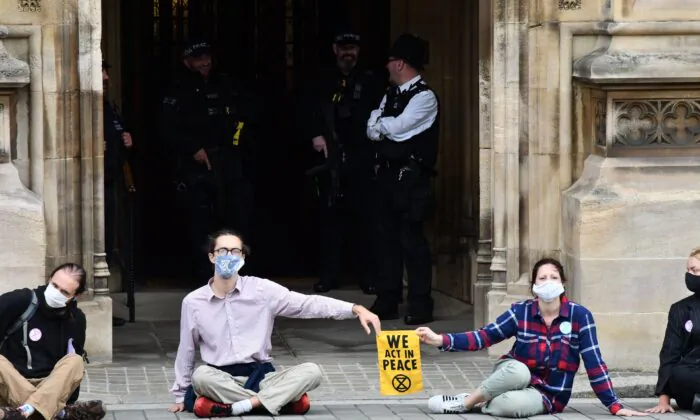 Activists from the climate protest group Extinction Rebellion sit glued to the pavement in front of one of the entrances to the Houses of Parliament in London on Sept. 3, 2020 (Justin Tallis/AFP via Getty Images)