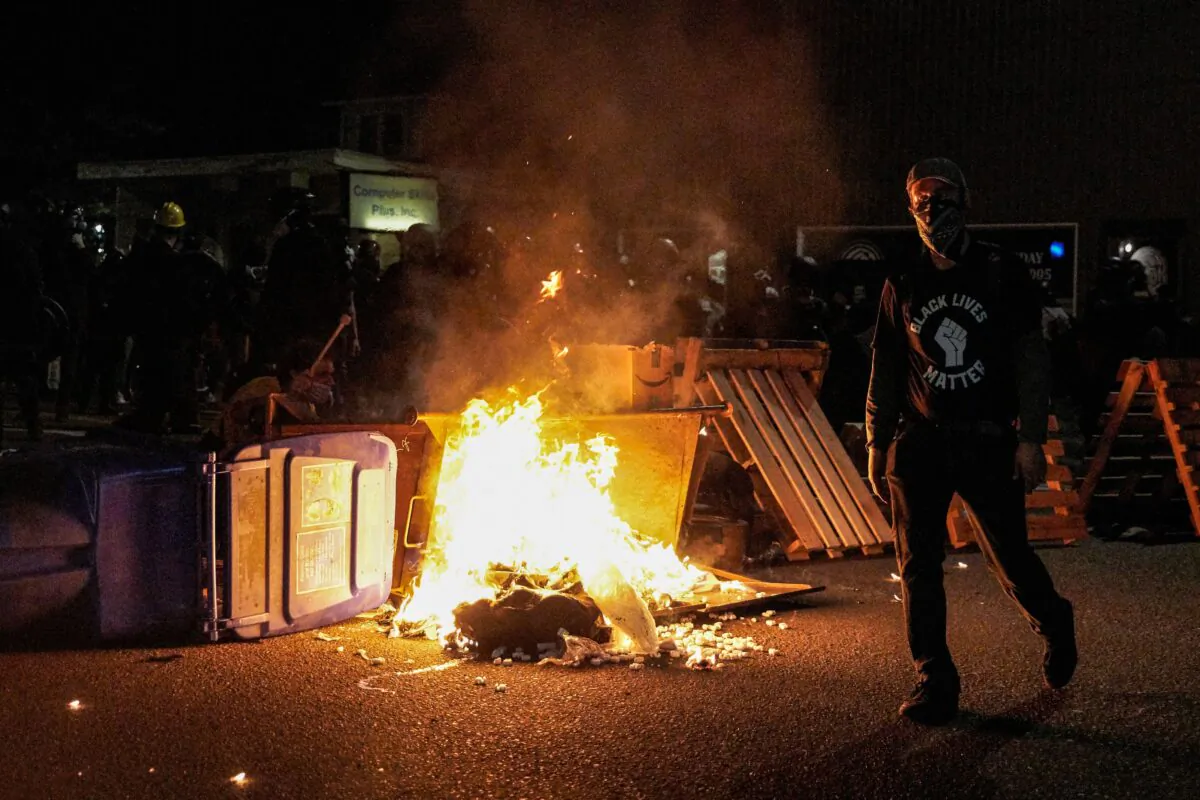 A man walks by a burning pile of debris in the street in Portland, Ore., on Sept. 5, 2020. (Allison Dinner/AFP via Getty Images)
