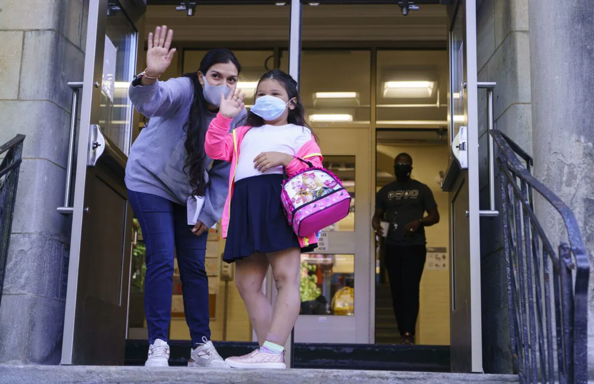 A child waves to her parents at the entrance to Bancroft Elementary School as students go back to school in Montreal on Aug. 31, 2020. (The Canadian Press/Paul Chiasson)