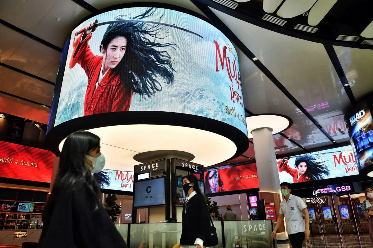 People walk past advertising displays for Disney's Mulan film at a cinema inside a shopping mall in Bangkok on Sept. 8, 2020. (Lillian Suwanrumpha/AFP via Getty Images)