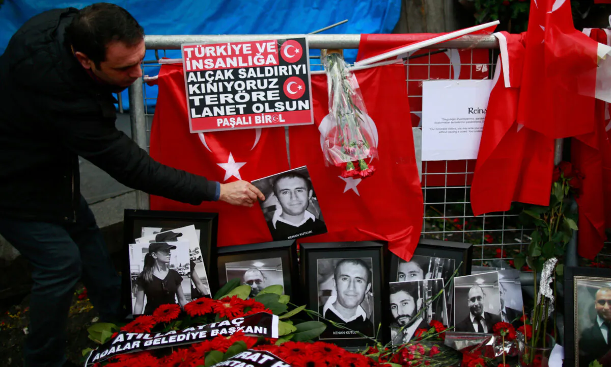In this Jan. 4, 2017 file photo, a man adjusts a victim's photograph displayed with floral tributes and Turkish flags, outside the Reina night club following the New Year's Eve attack, in Istanbul, Turkey. (Emrah Gurel/AP Photo)