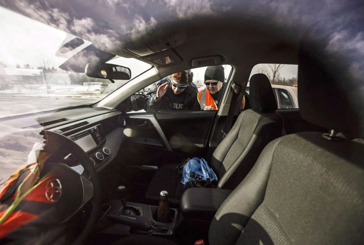 An RCMP officer and a Citizens on Patrol volunteer check a car for valuables to warn the owner about the risk of leaving valuables in a vehicle, in Ardrossan, Alta., on March 6, 2018. (The Canadian Press/Jason Franson)