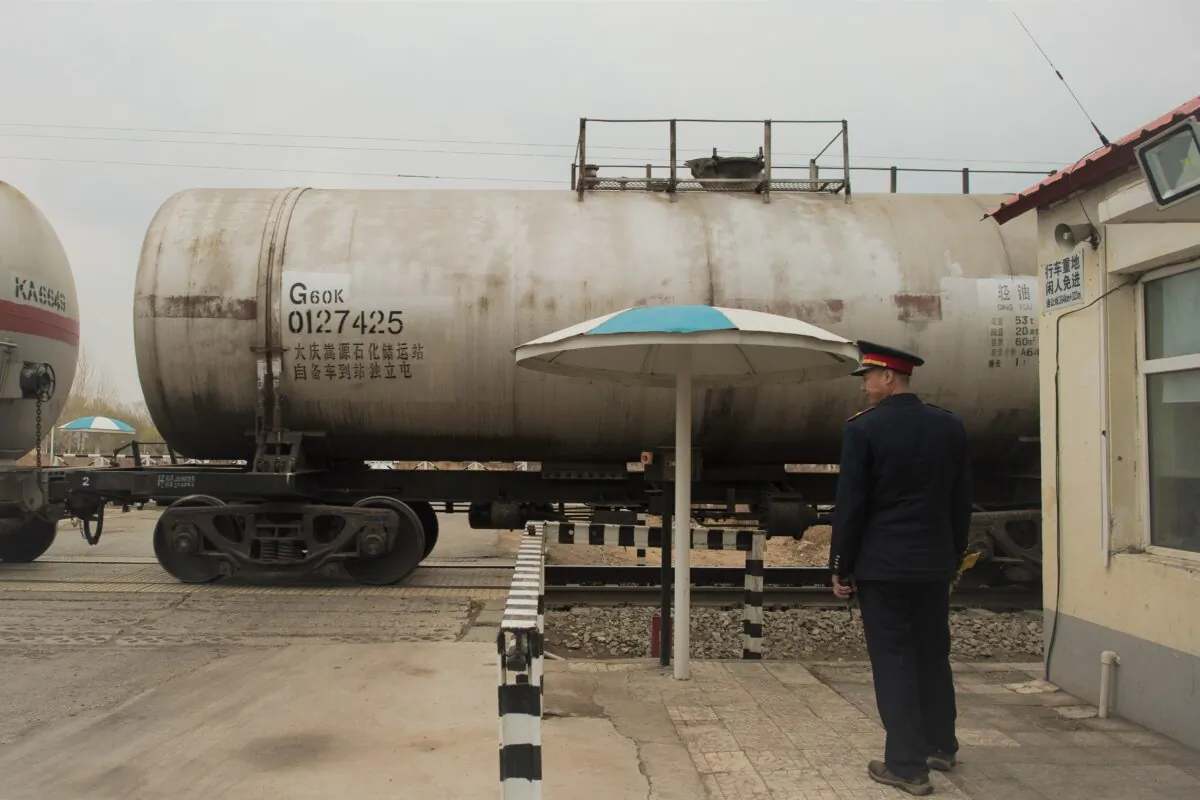 An officer watches an oil transporting train at a railway crossing in Daqing, China, on May 2016.  (Nicolas Asfouri AFP via Getty Images)