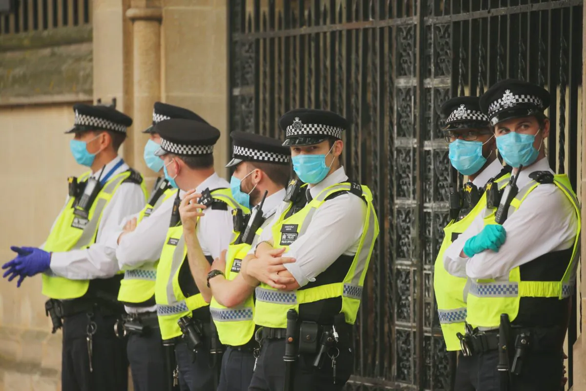 Police officers stand wearing facemasks as a precaution against the transmission of CCP virus, in London on Sept. 9, 2020. (Isabel Infantes/AFP via Getty Images)