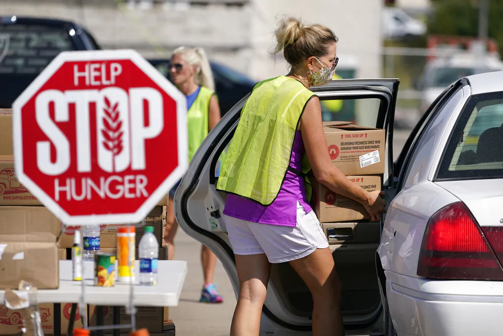 A volunteer loads a local resident's vehicle at a drive-up produce giveaway organized by a Des Moines food pantry on Aug. 28, 2020, in Des Moines, Iowa. (AP Photo/Charlie Neibergall)